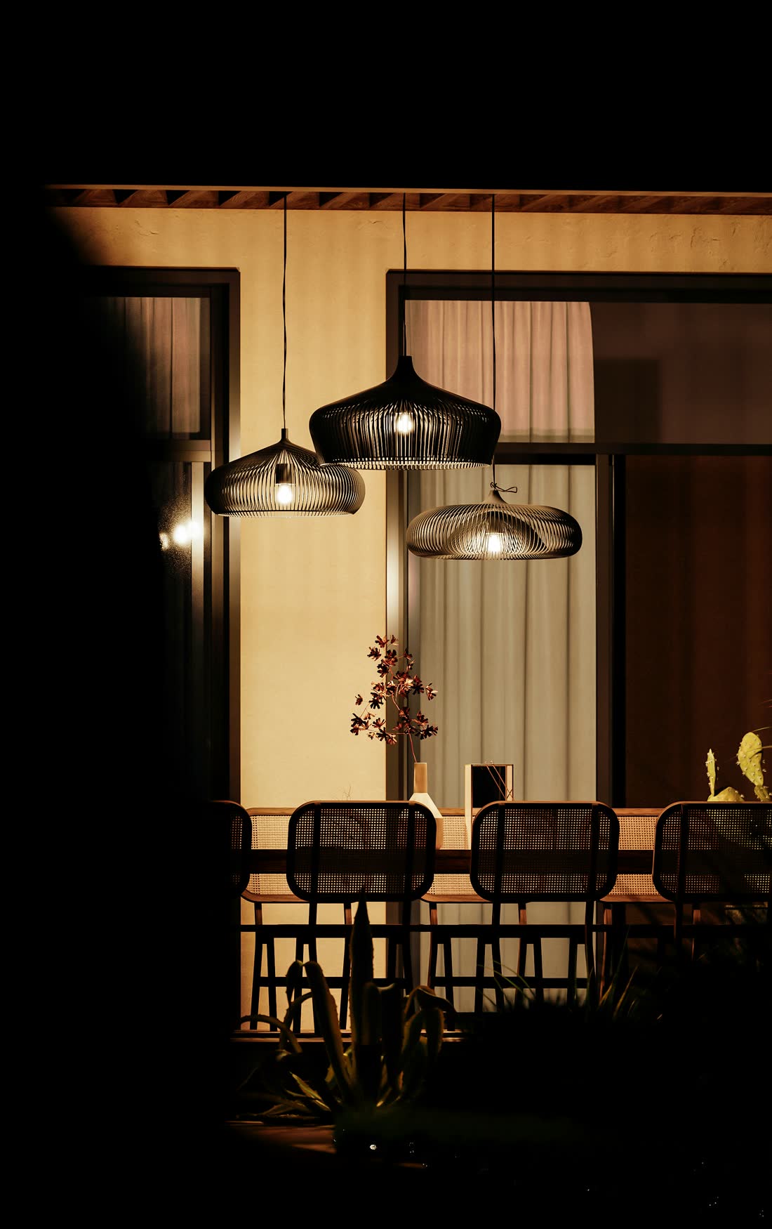A warm restaurant patio at dusk lit by sculptural pendant lights