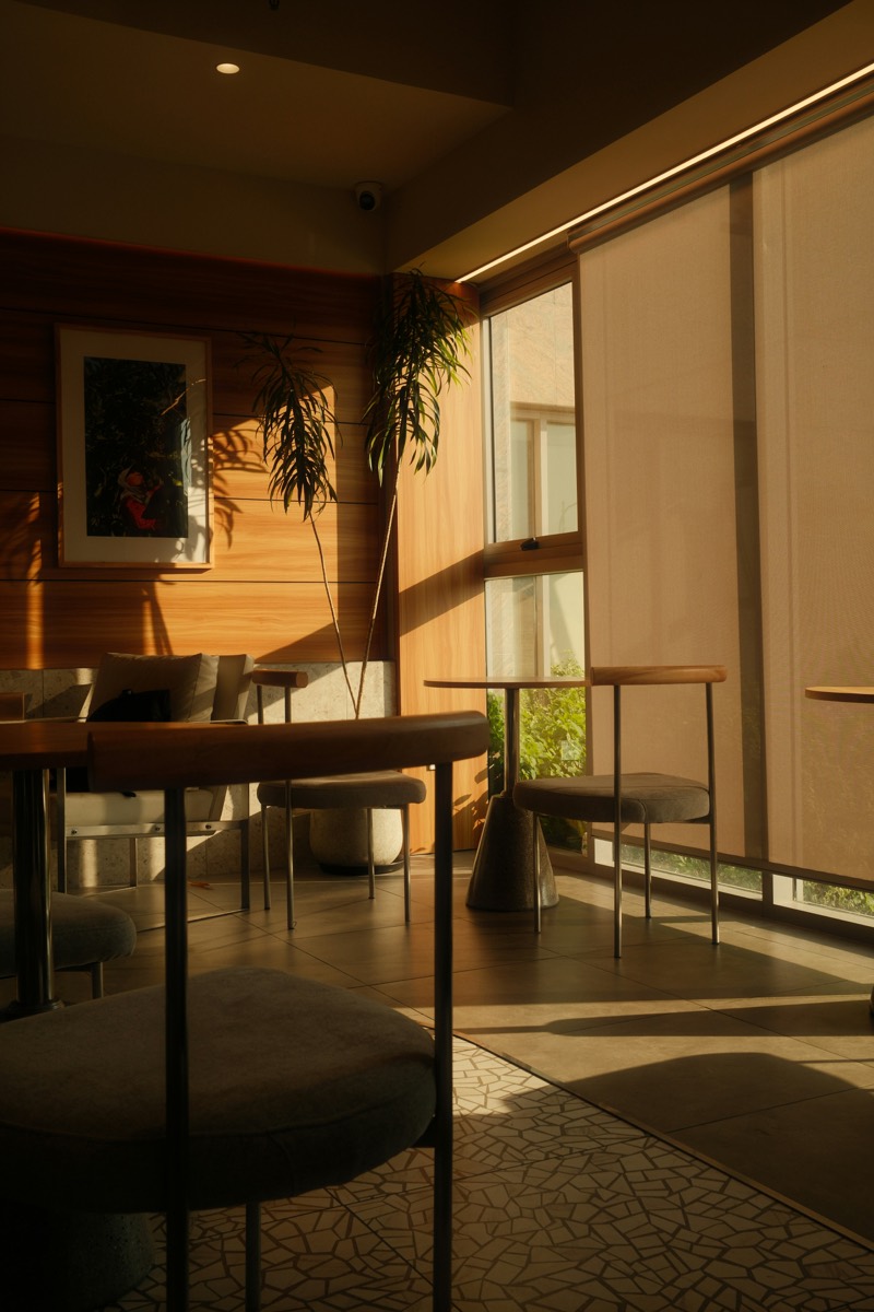 A warm, golden-lit lounge with bistro seating and soft motorized shades