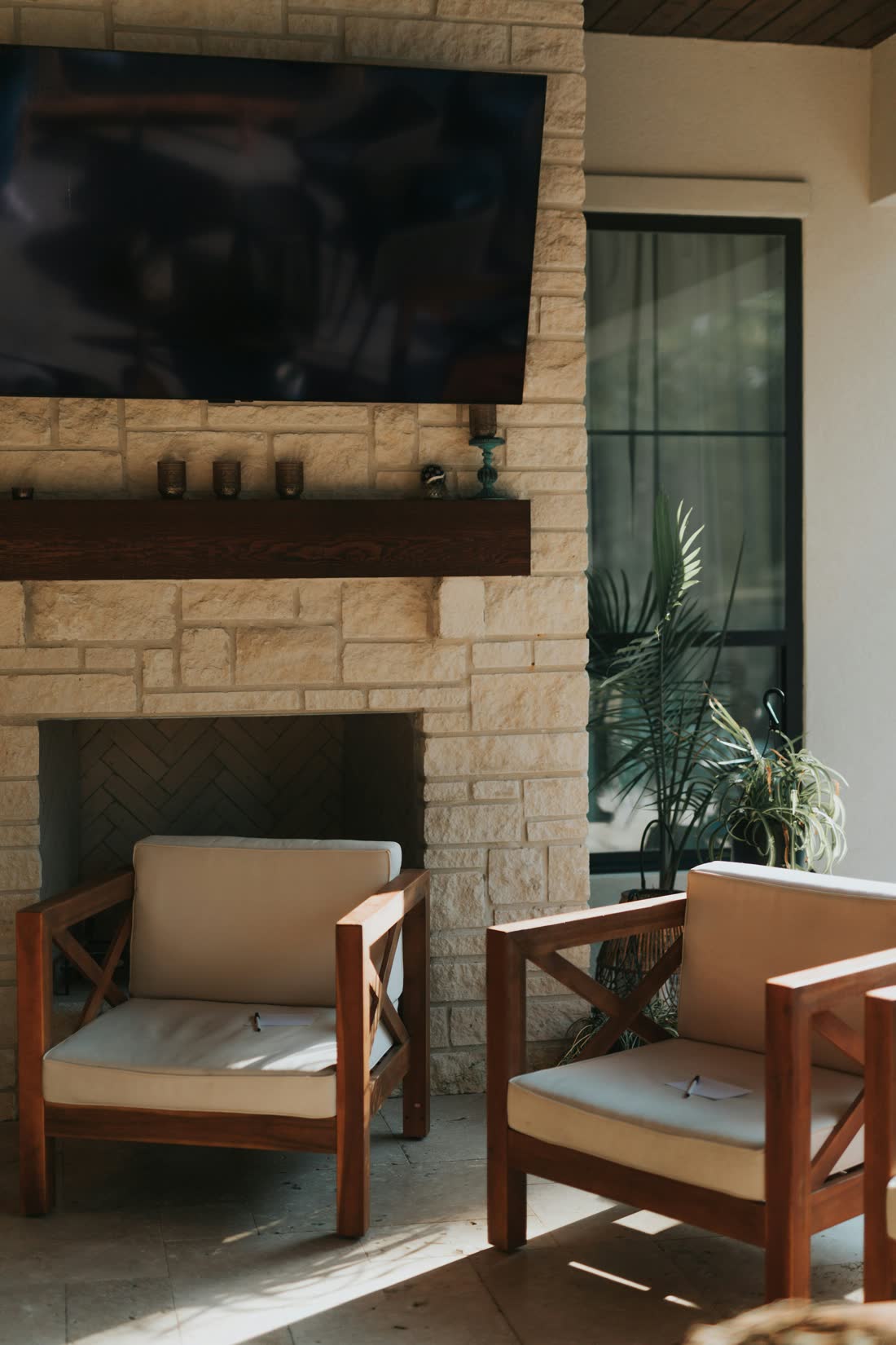 A covered Florida lanai with a weatherproof television above a stone fireplace